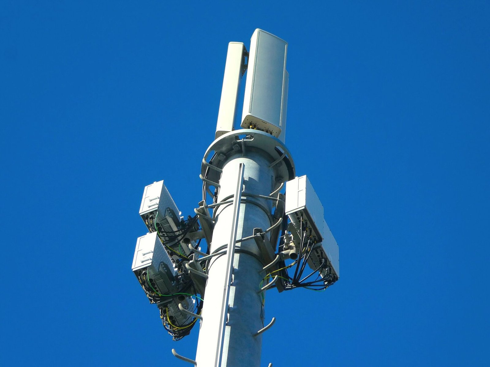 Wireless antennas mounted at the top of a communications mast against open sky.