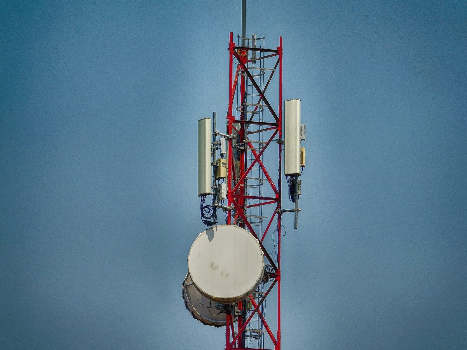A red and white tower carrying panel antennas and a microwave dish.