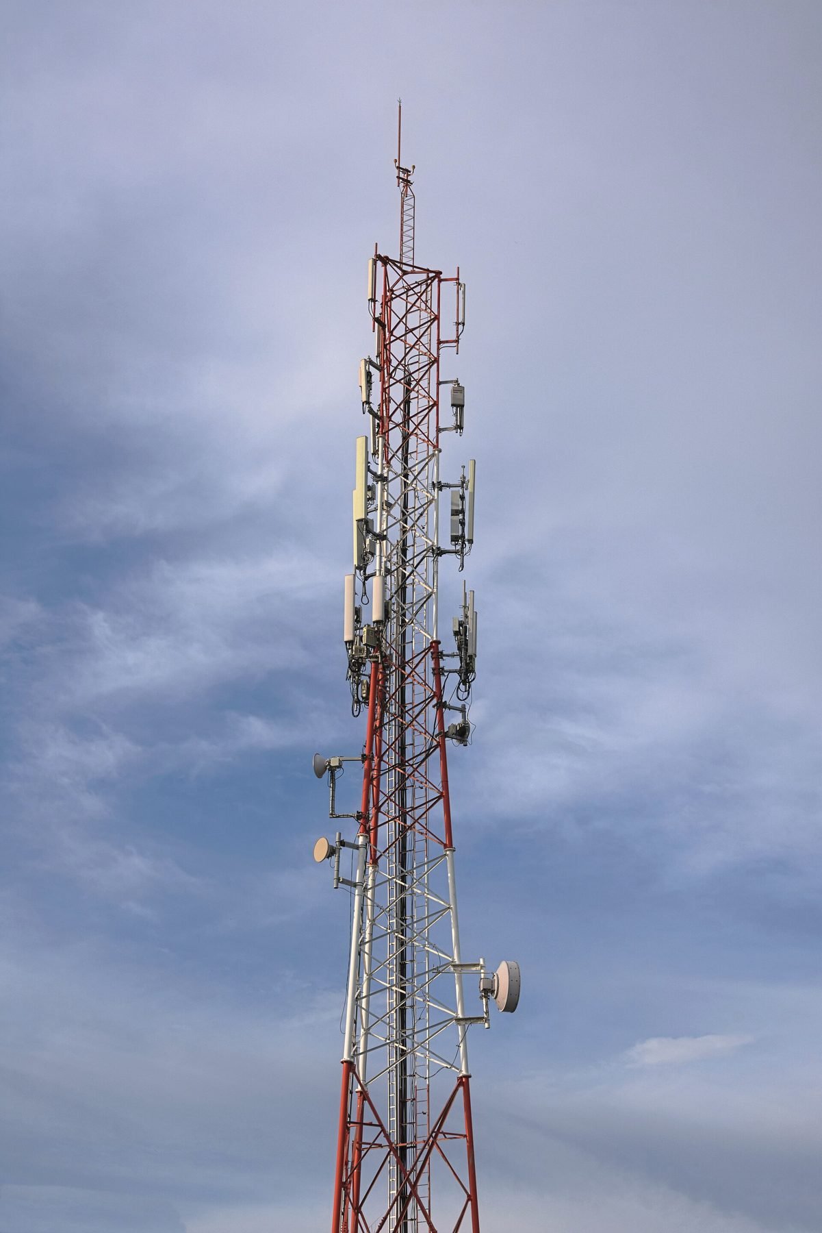 A guyed communications tower rising into a grey sky.