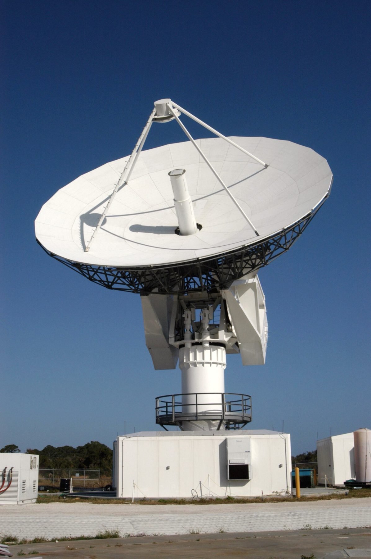 A large parabolic satellite communications dish on a concrete base.