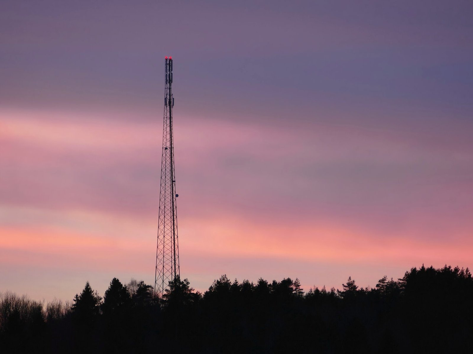 Communication towers silhouetted against a pink and blue dusk sky.